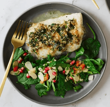 Grilled fish fillet with herb sauce and spinach salad, fresh seafood meal