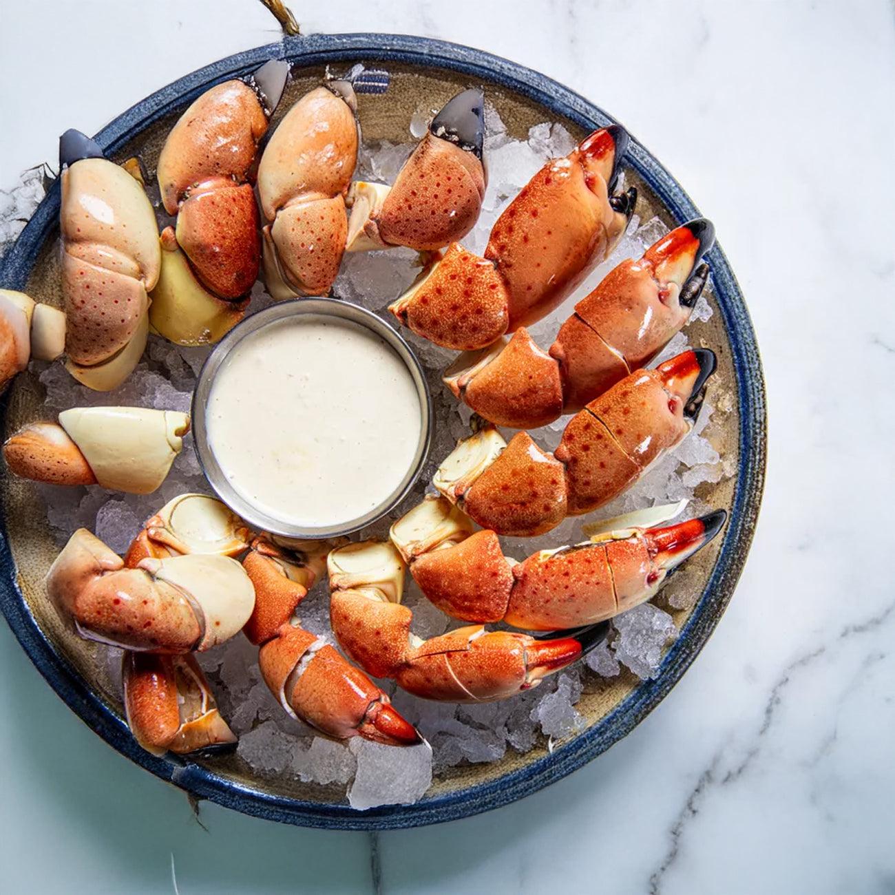 Fresh crab claws on ice with dipping sauce, ready for seafood lovers in Southwest Florida