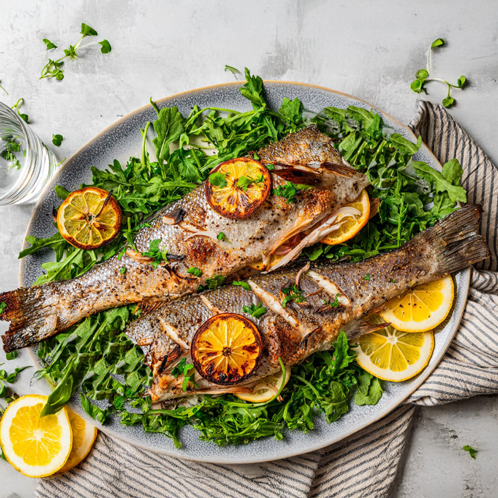 Grilled whole fish with lemon slices and arugula, fresh seafood meal