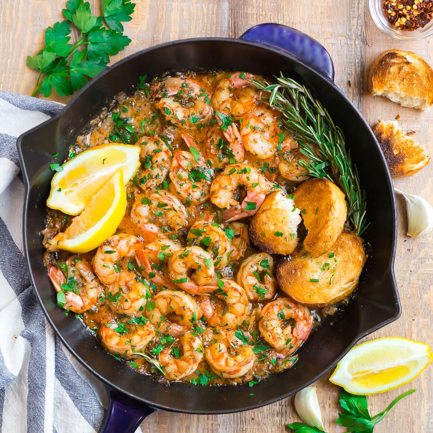 Garlic butter shrimp in cast iron skillet with lemon, herbs, and toasted bread, fresh seafood meal