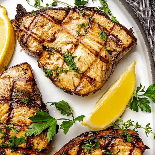 Grilled fish steaks with lemon wedges and fresh herbs, perfect for seafood lovers in Southwest Florida