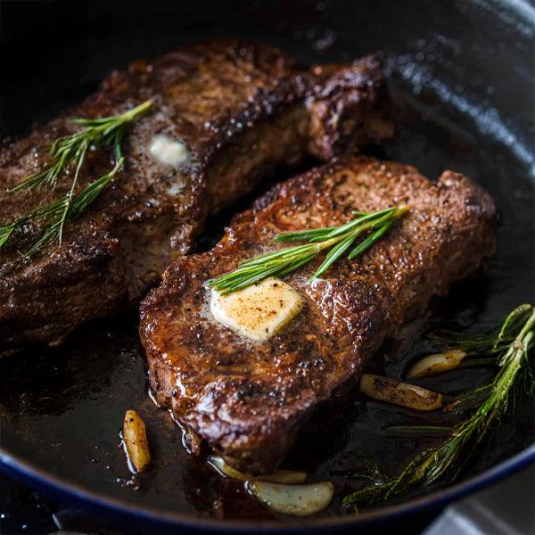 Seared steak with rosemary and butter in cast iron skillet, fresh gourmet meal